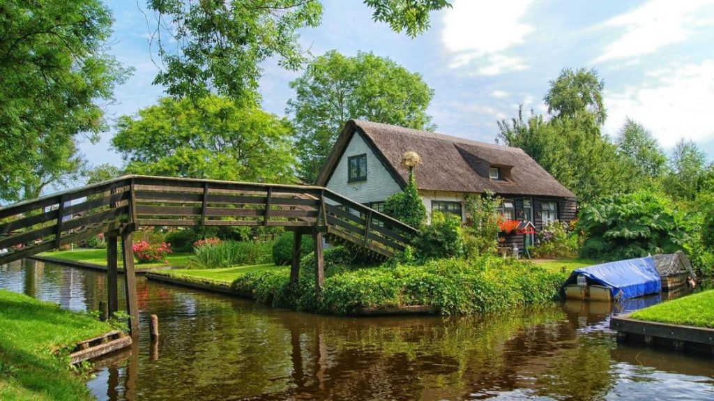Elektrische punter voor varen in Giethoorn met uitzicht op bruggen en traditionele huizen in het waterrijke dorp